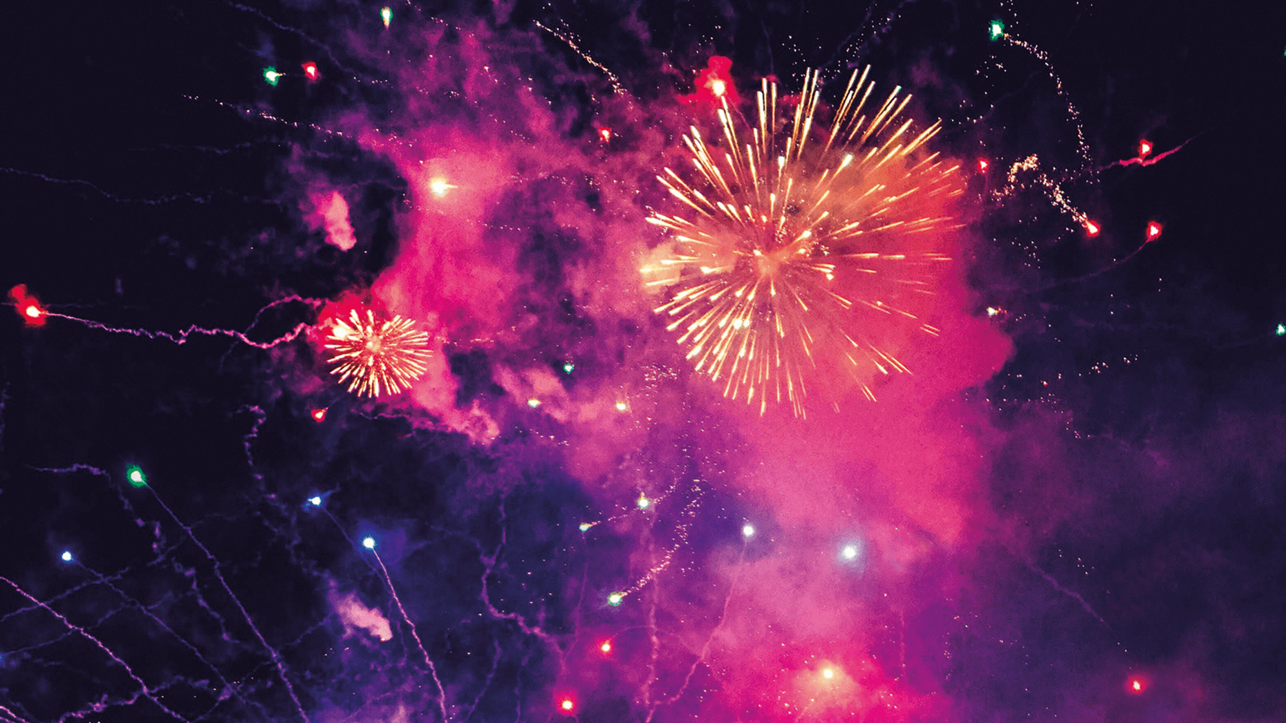 Pink-violett-gelbes Neujahrsfeuerwerk vor schwarzen Himmel