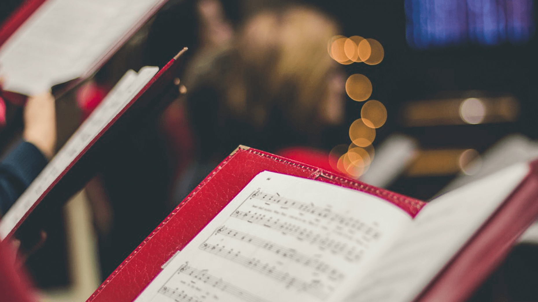 Aufgeschlagene Noten in rotem Umschlag in weihnachtlich beleuchteter Kirche