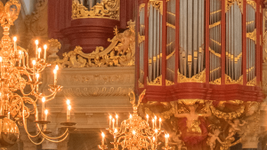 Rot-goldene Orgel mit brennendem Kronleuchter davor